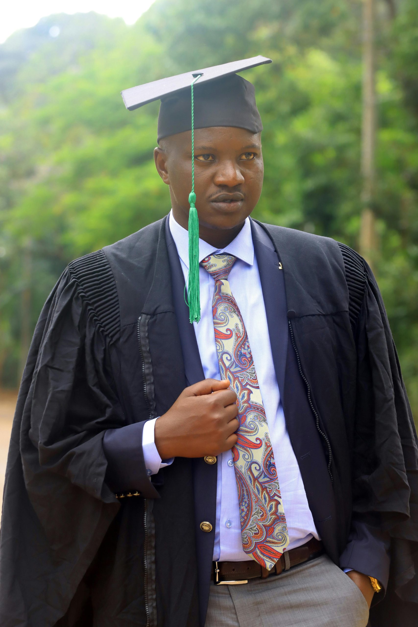 A graduate stands outdoors wearing a cap and gown, symbolizing success and achievement.
